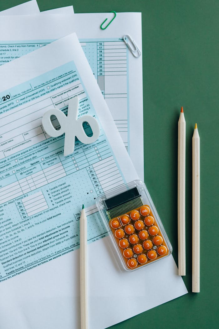 why-choose-us-01 Flat lay of tax documents, calculator, and pencils on green surface.